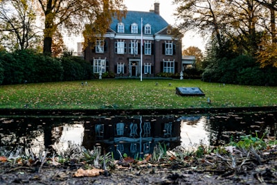 Elegant brick mansion with manicured gardens and golden light at sunset.