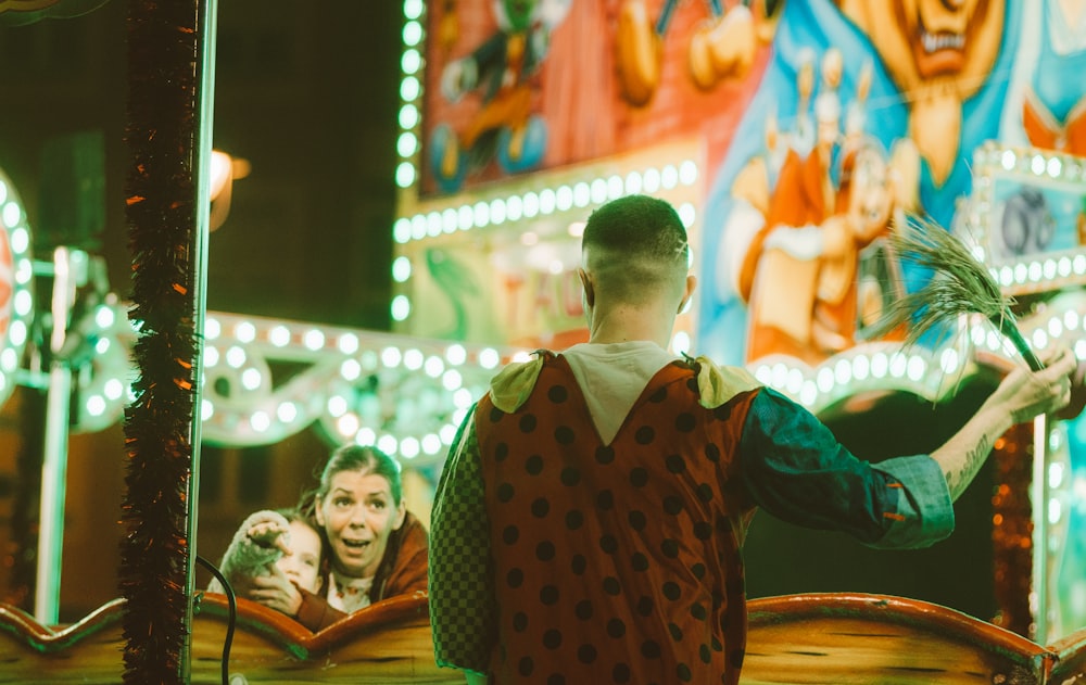 a man in a clown costume standing in front of a carnival ride