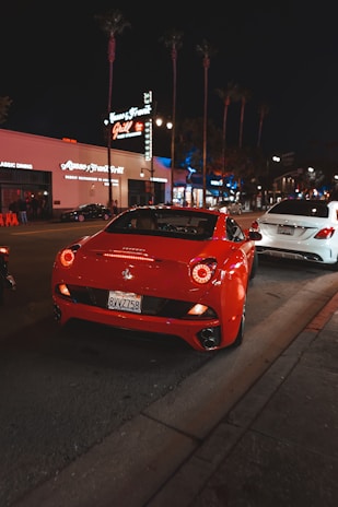 A red sports car gleaming under city lights with Medellín’s skyline in the background.