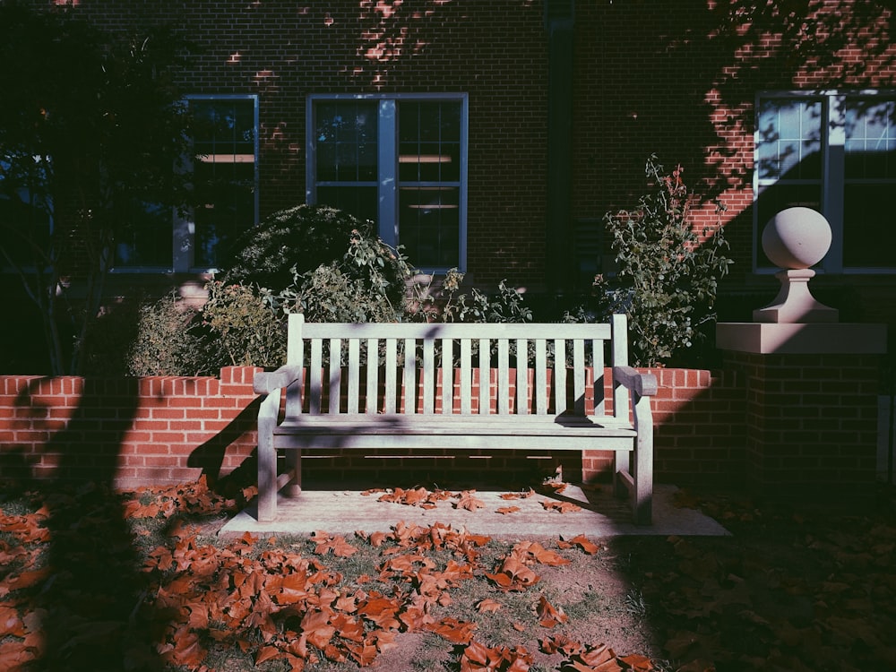 a white bench sitting in front of a brick building