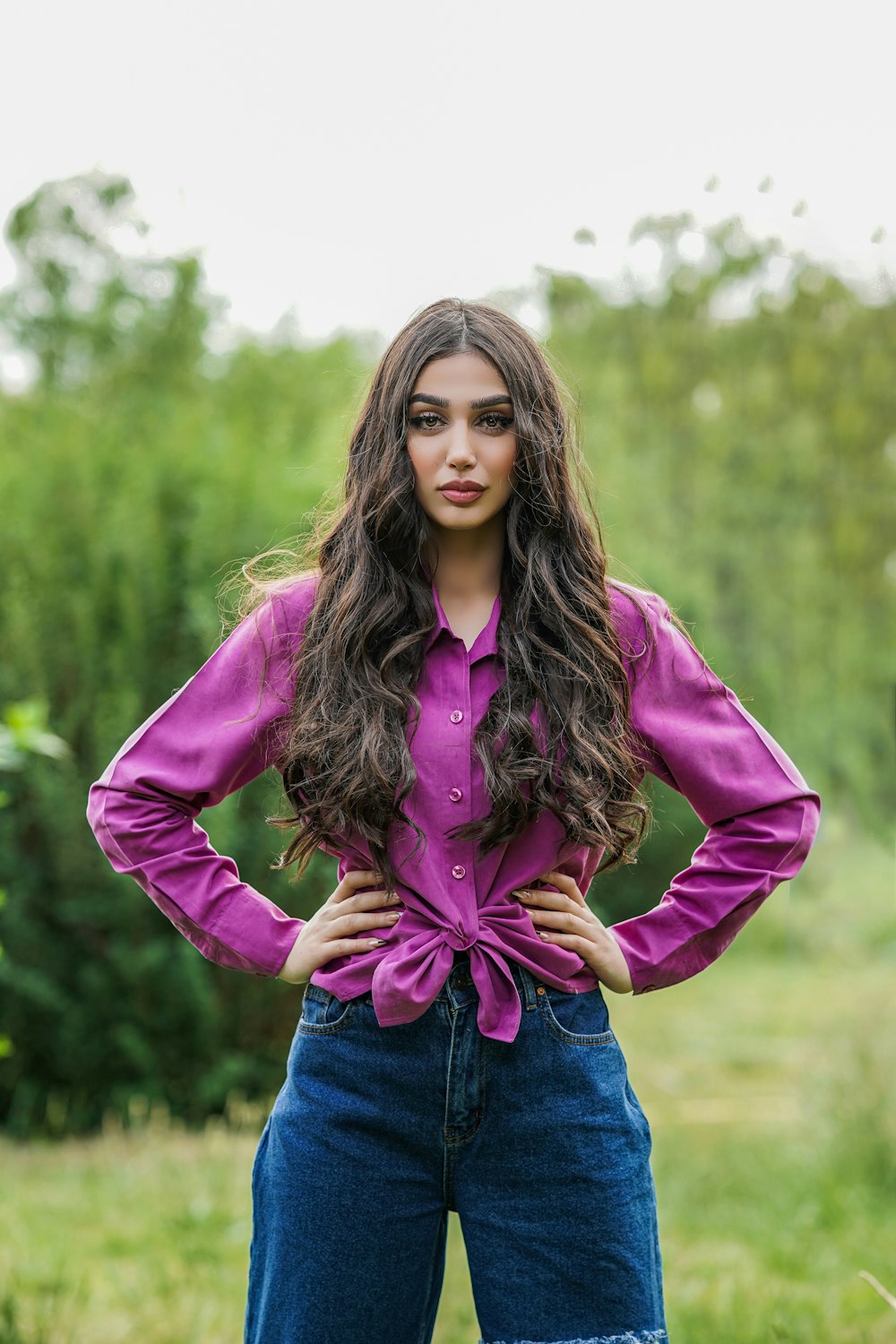 a woman standing in a field with her hands on her hips