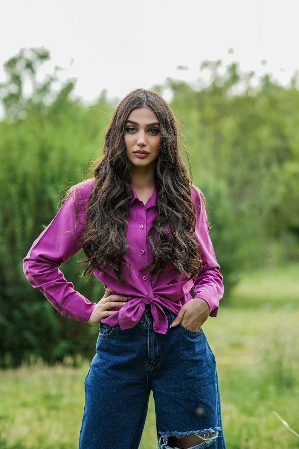 a woman standing in a field with her hands on her hips