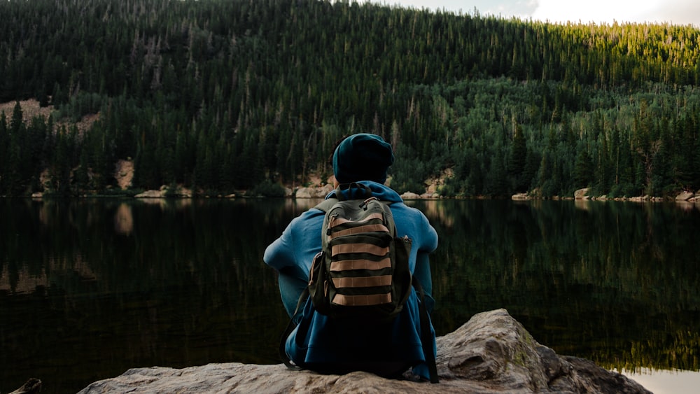 a person sitting on a rock looking at a lake