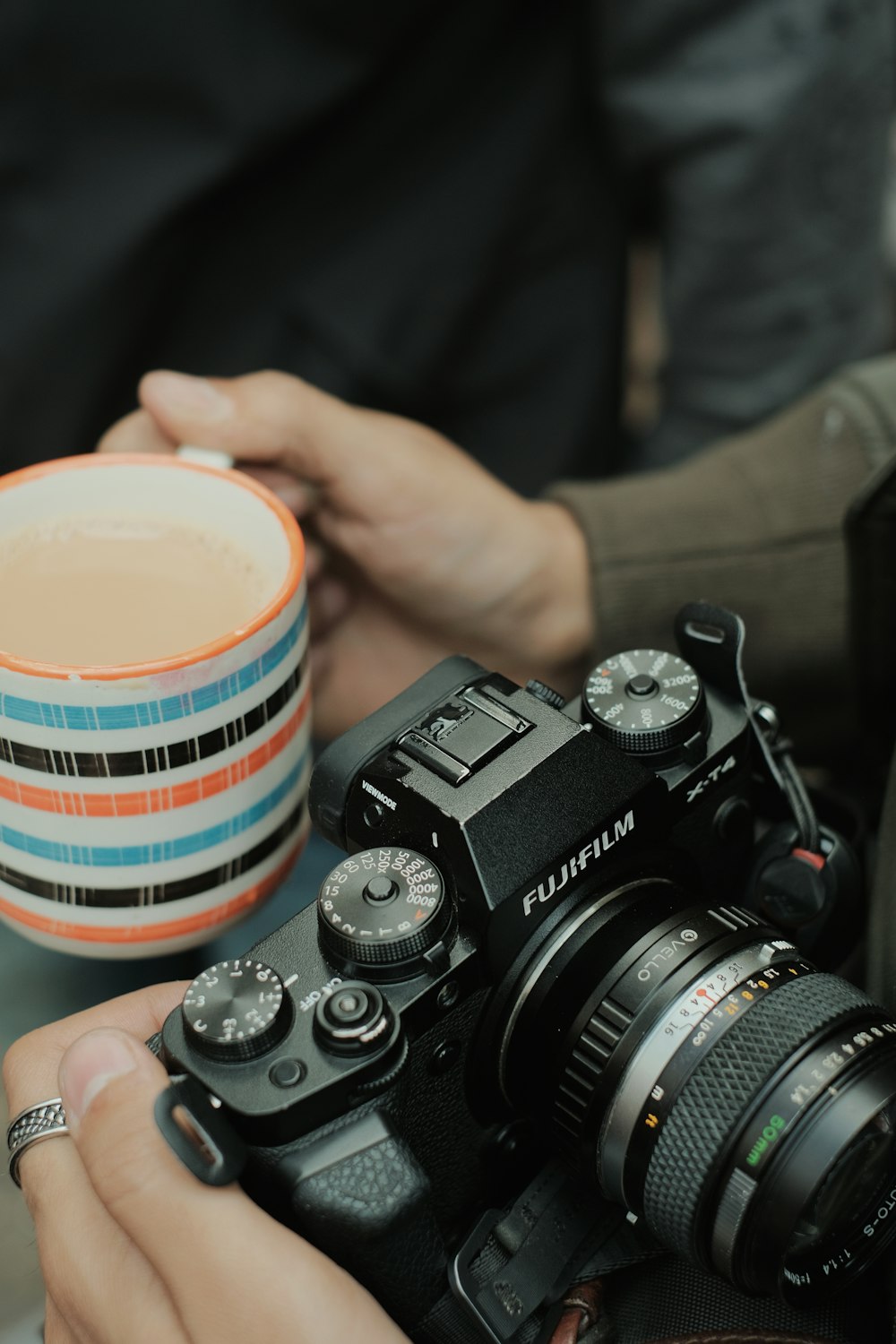 a person holding a camera and a coffee mug