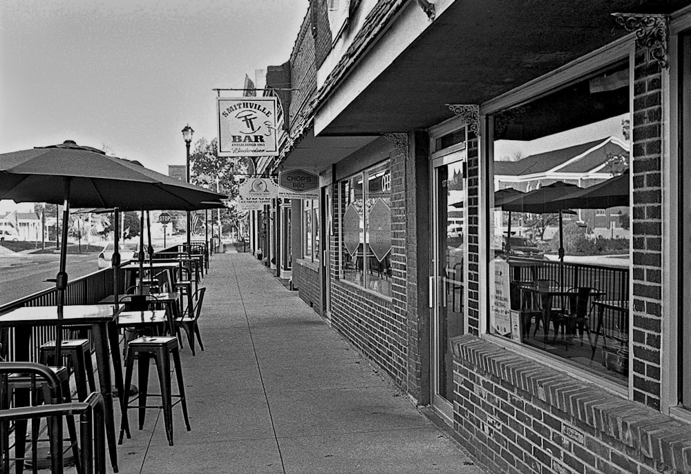 a sidewalk lined with tables and chairs next to a building