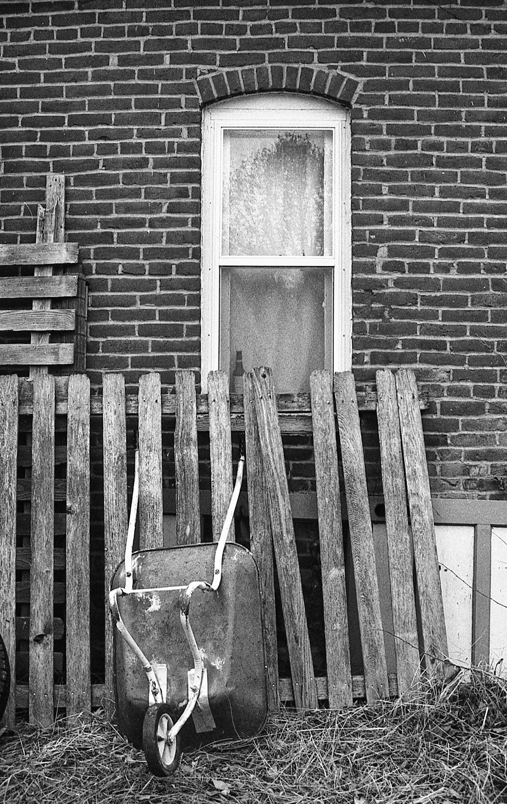 a black and white photo of a wheelbarrow next to a brick building