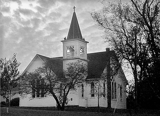 Historic church building with traditional Baptist architecture surrounded by trees.