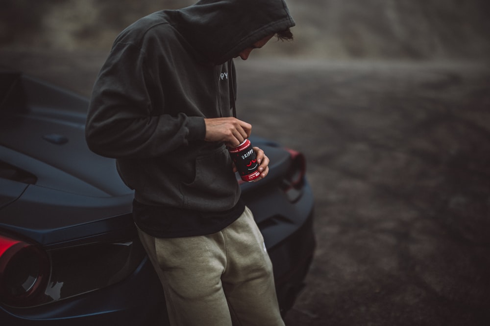 um homem de pé ao lado de um carro esportivo olhando para seu telefone celular