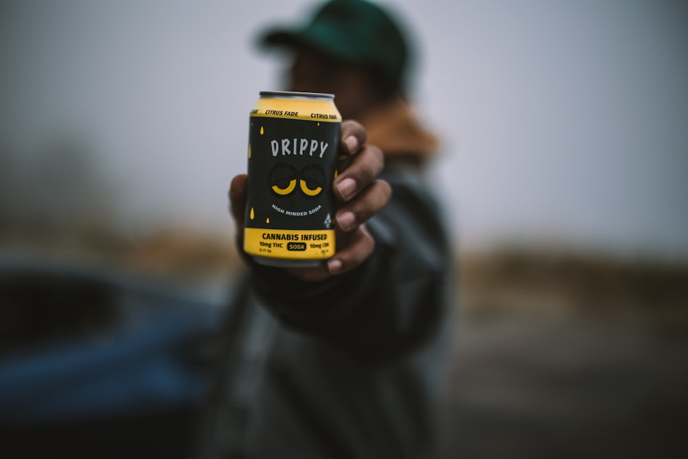 a man holding up a can of beer