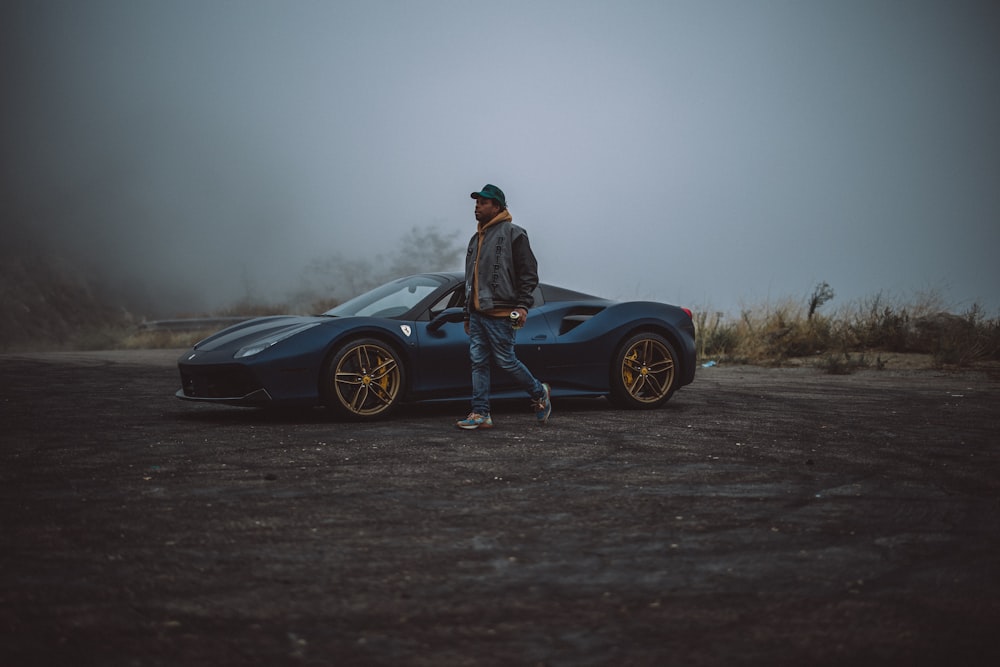a man standing next to a blue sports car