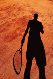 Black and white photo of Helson Davi Barros holding a tennis racket on a clay court in Recife.