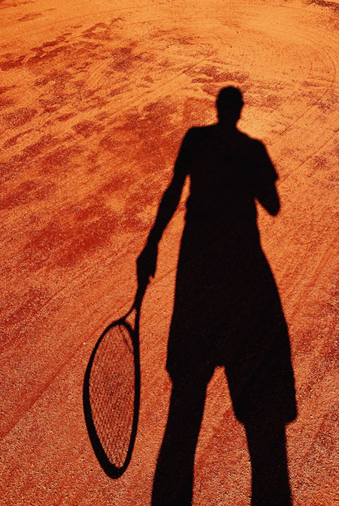 Black and white photo of Helson Davi Barros holding a tennis racket on a clay court in Recife.