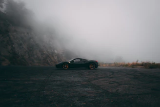 A sleek luxury car parked with the misty Mussoorie hills in the background at dawn.