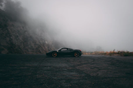 A sleek luxury car parked with the misty Mussoorie hills in the background at dawn.