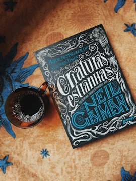 Stylish hardcover books stacked with gold accents next to a midnight blue ceramic cup.