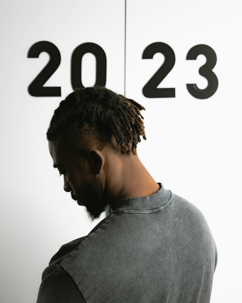 a man with dreadlocks standing in front of a wall