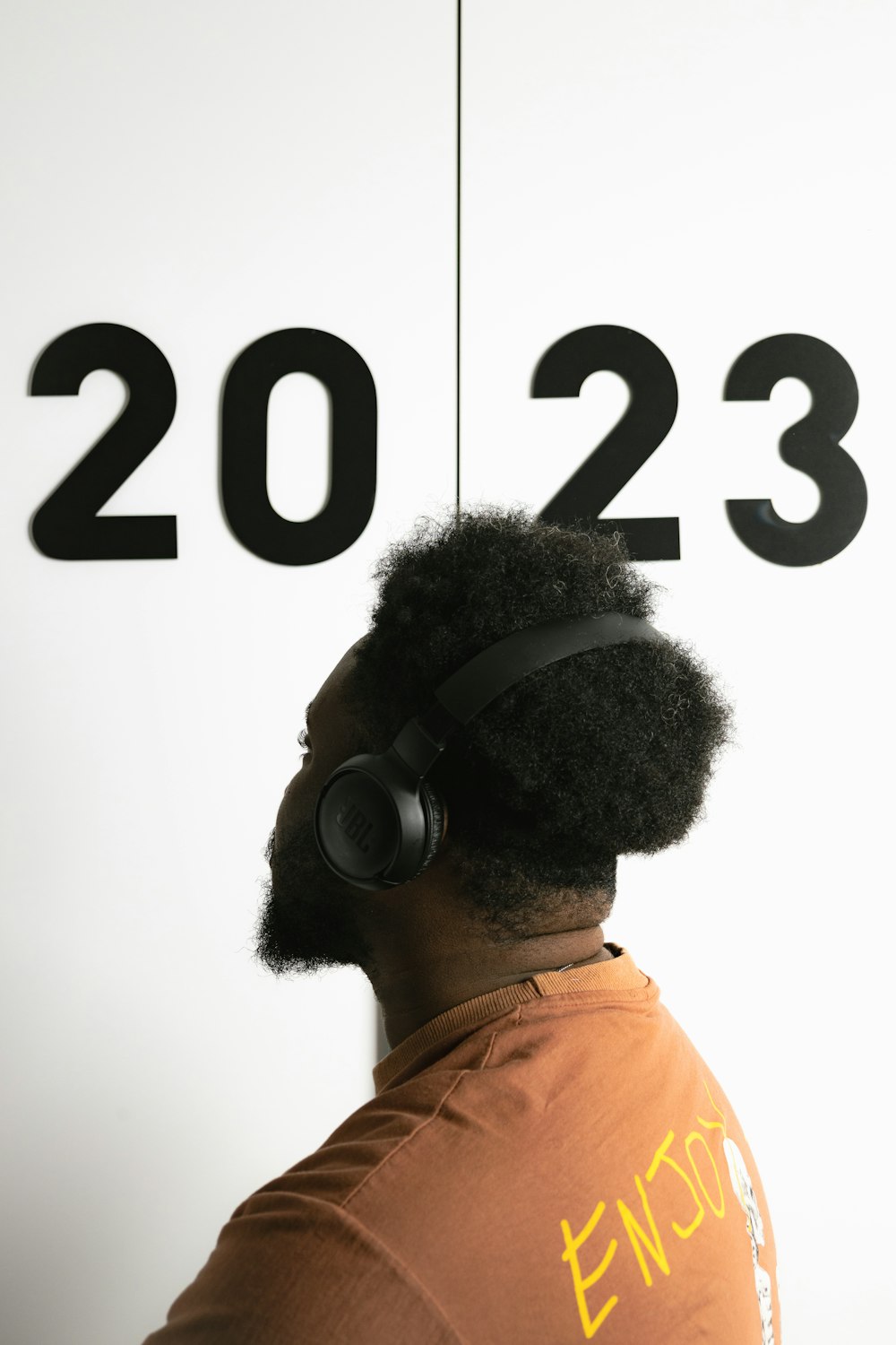 a man wearing headphones standing in front of a sign