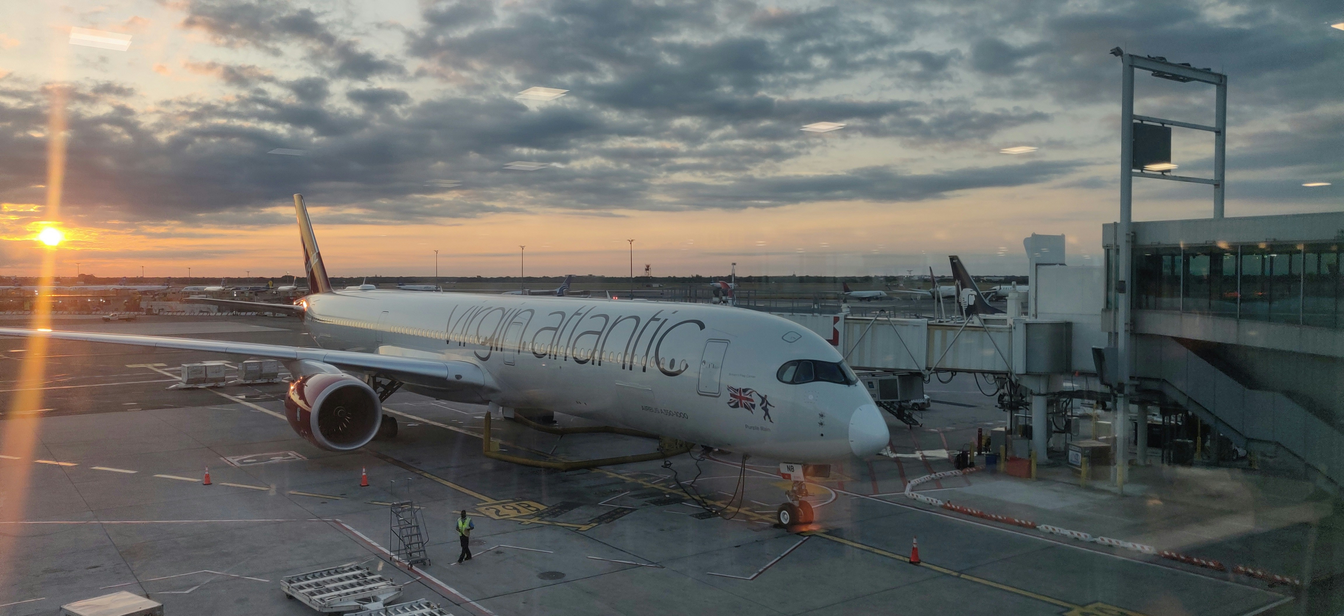 an airplane is parked on the tarmac at an airport, A Virgin Atlantic Airbus A350-1000 at John F. Kennedy Airport during sunrise
