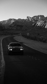 A dynamic photo of a travel influencer capturing a scenic mountain road with a sleek car.