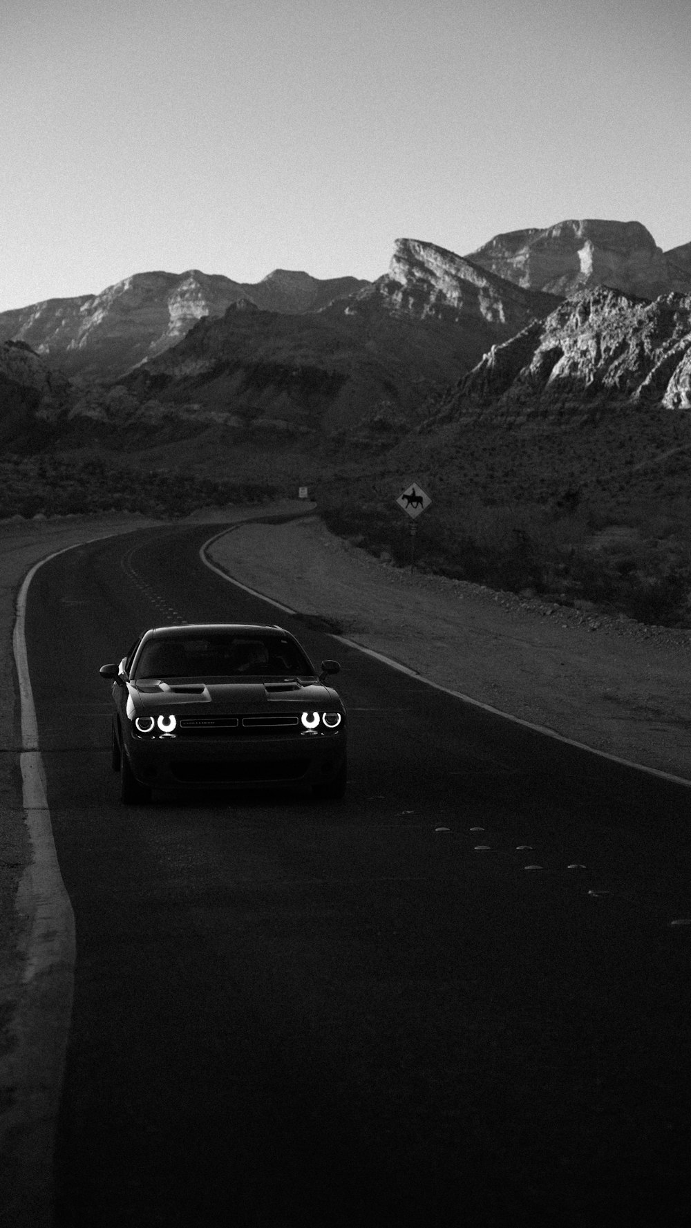 a car driving down a road with mountains in the background