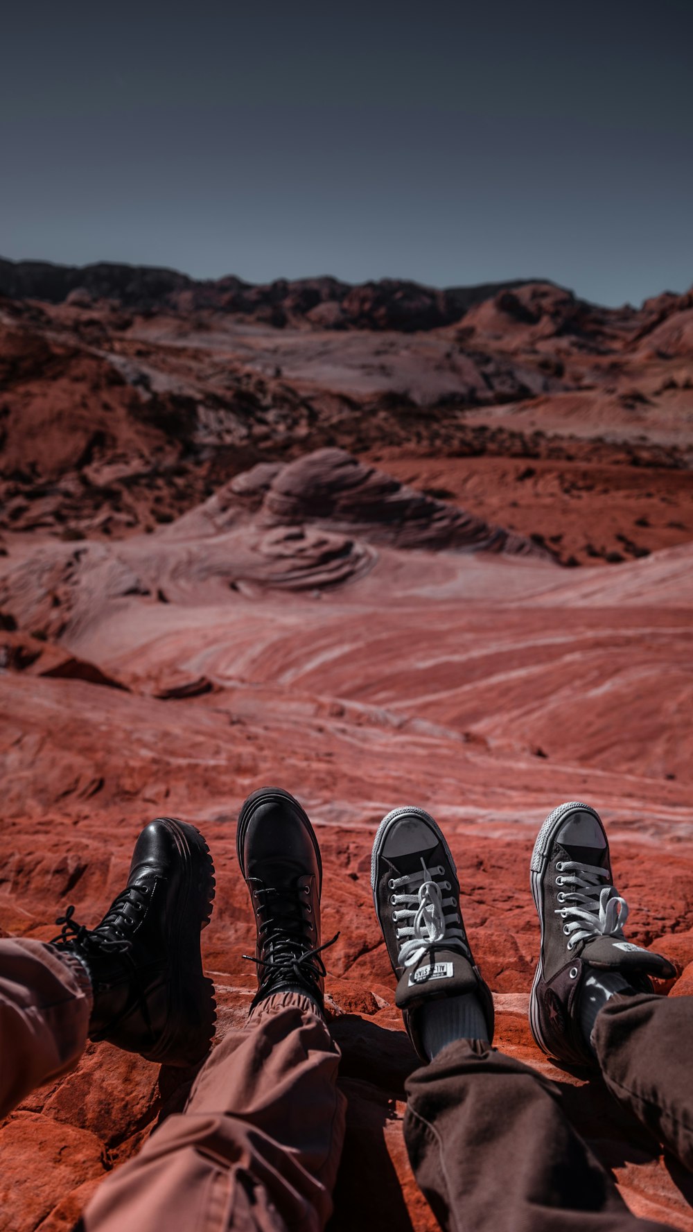 a couple of people sitting on top of a red rock