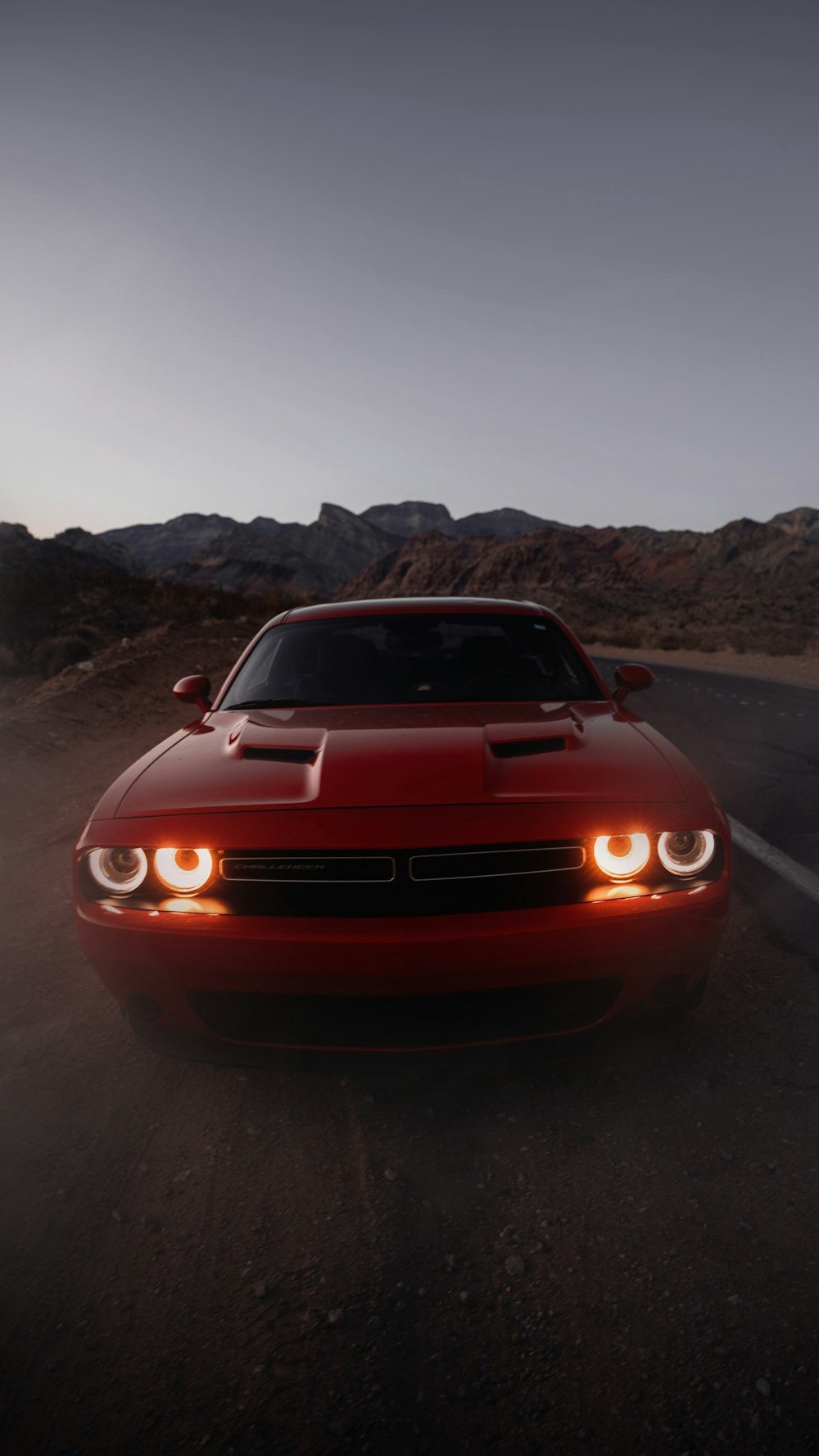 a red car driving down a desert road