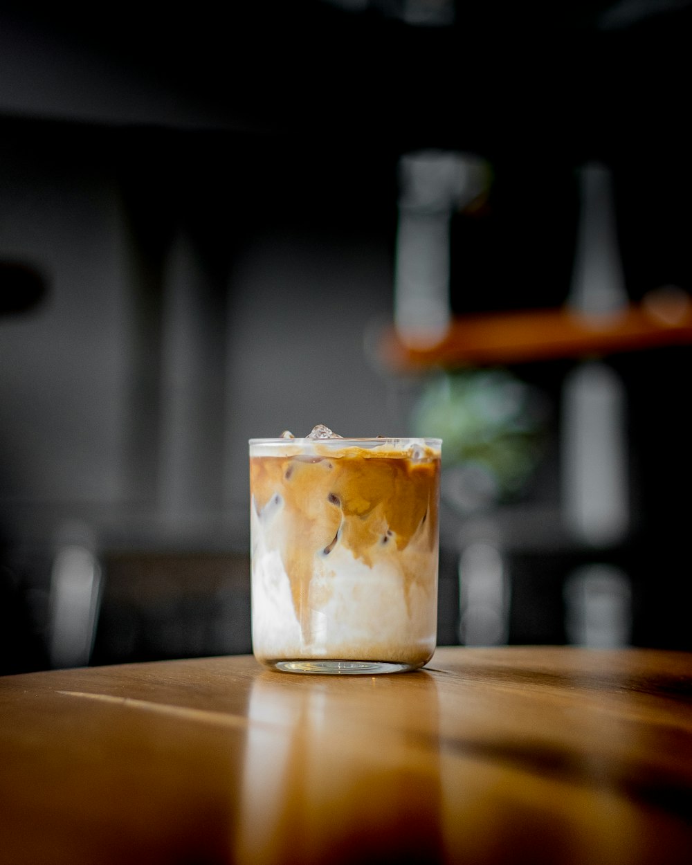 a glass filled with liquid sitting on top of a wooden table