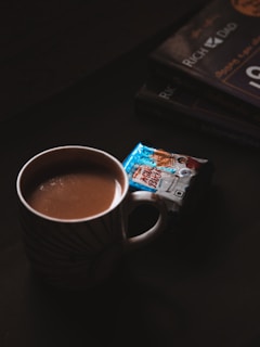 a cup of hot chocolate next to a stack of books
