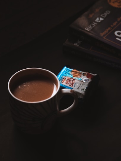 a cup of hot chocolate next to a stack of books