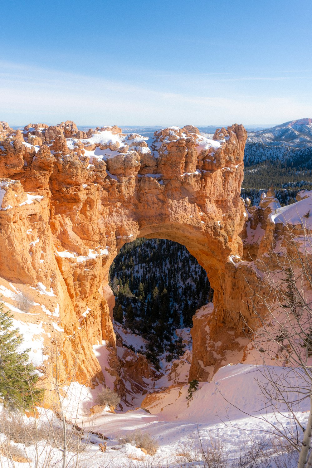 a snow covered landscape with a rock arch in the middle