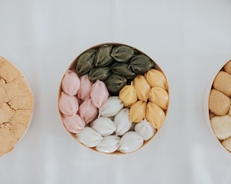 An assortment of colorful, bite-sized sweets arranged on a light wooden tray, inviting and fresh.