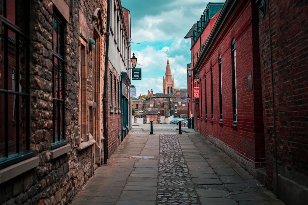 a narrow street with a red brick building in the background