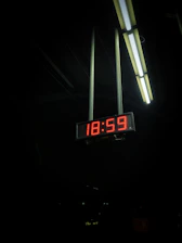 a digital clock hanging from the ceiling of a building