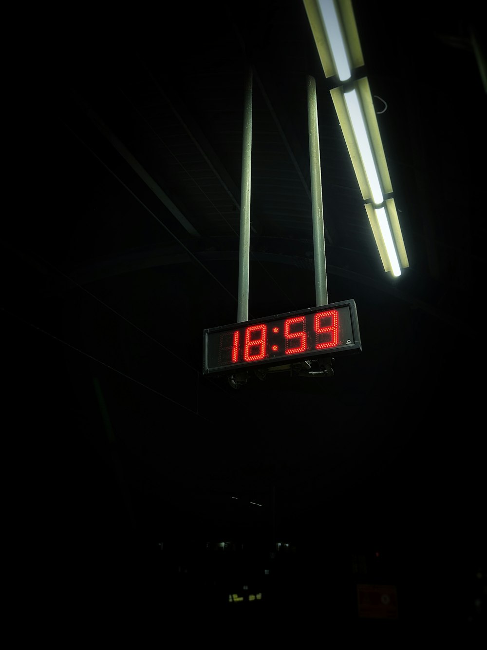 a digital clock hanging from the ceiling of a building
