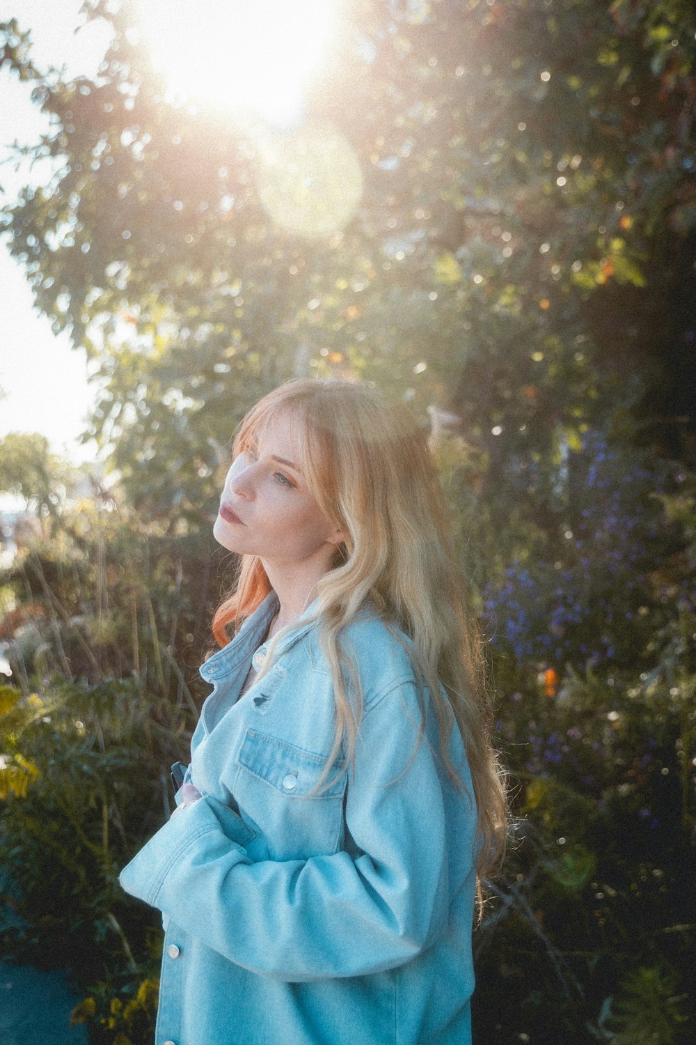 a woman in a blue jacket standing in a garden