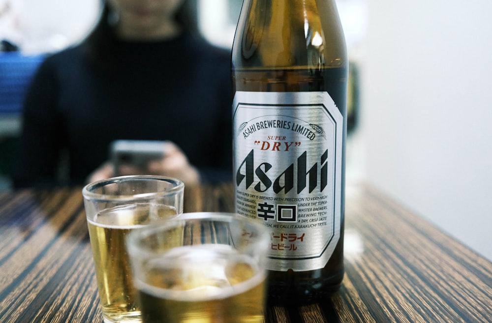 una donna seduta a un tavolo con una bottiglia di birra