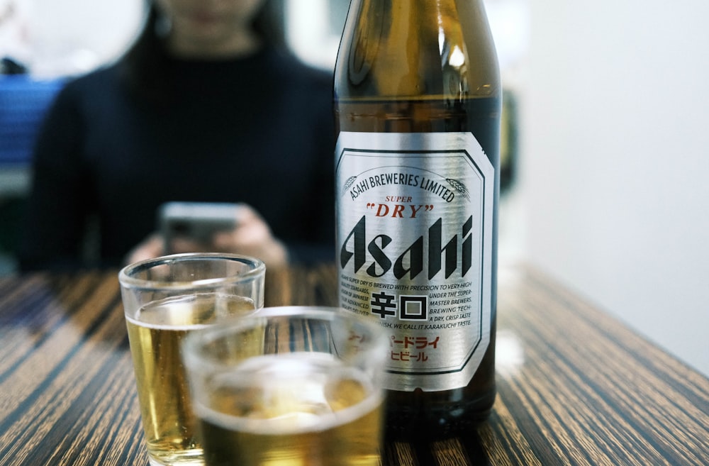 a woman sitting at a table with a bottle of beer