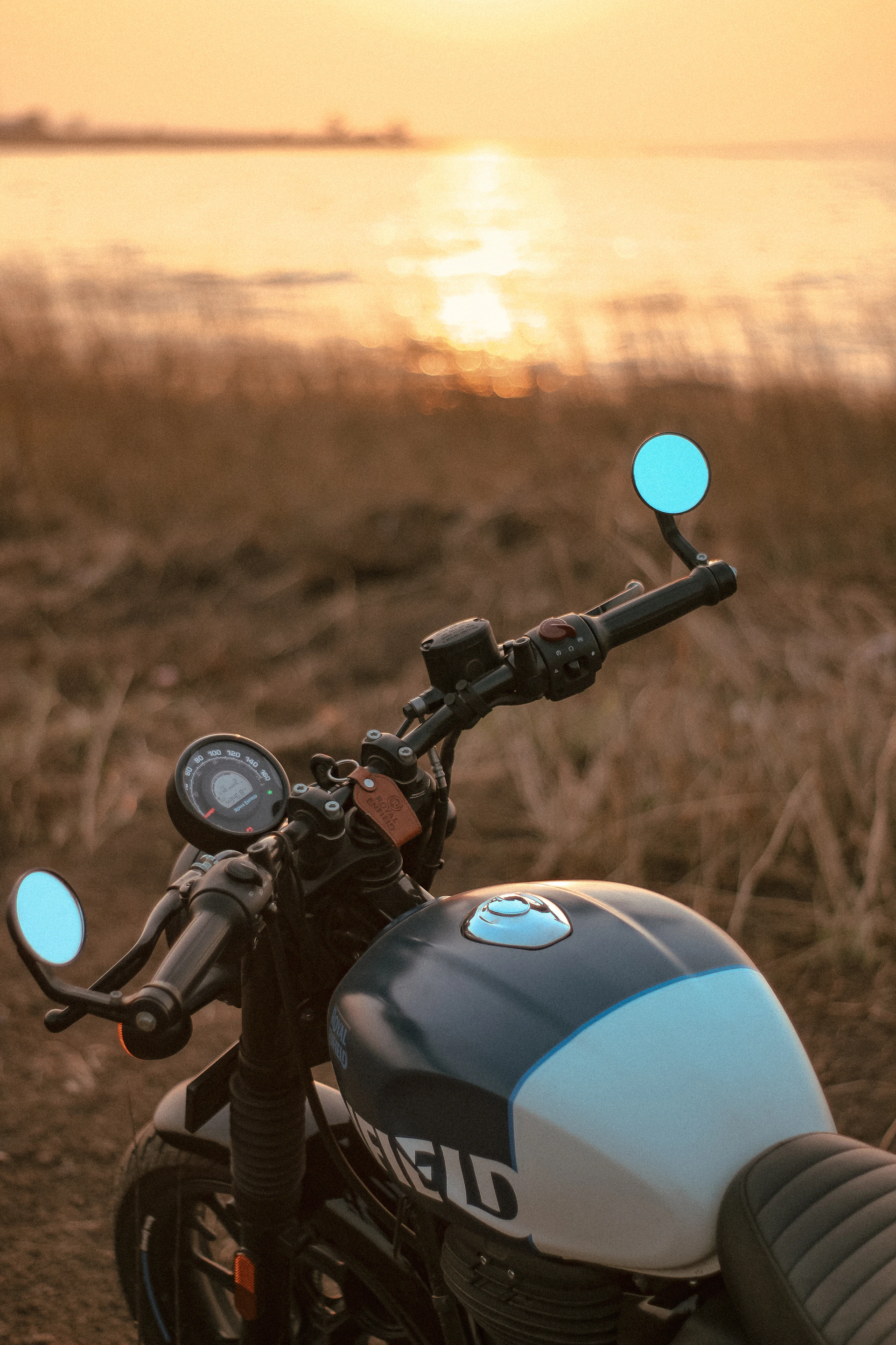 Motorcycle parked at sunset with vibrant blue LED accent lights illuminating its frame.
