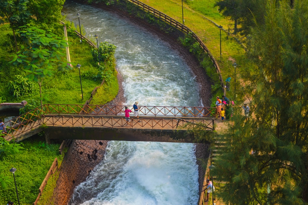 a group of people walking across a bridge over a river