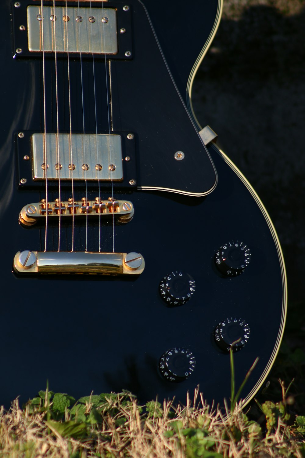 a black electric guitar sitting in the grass