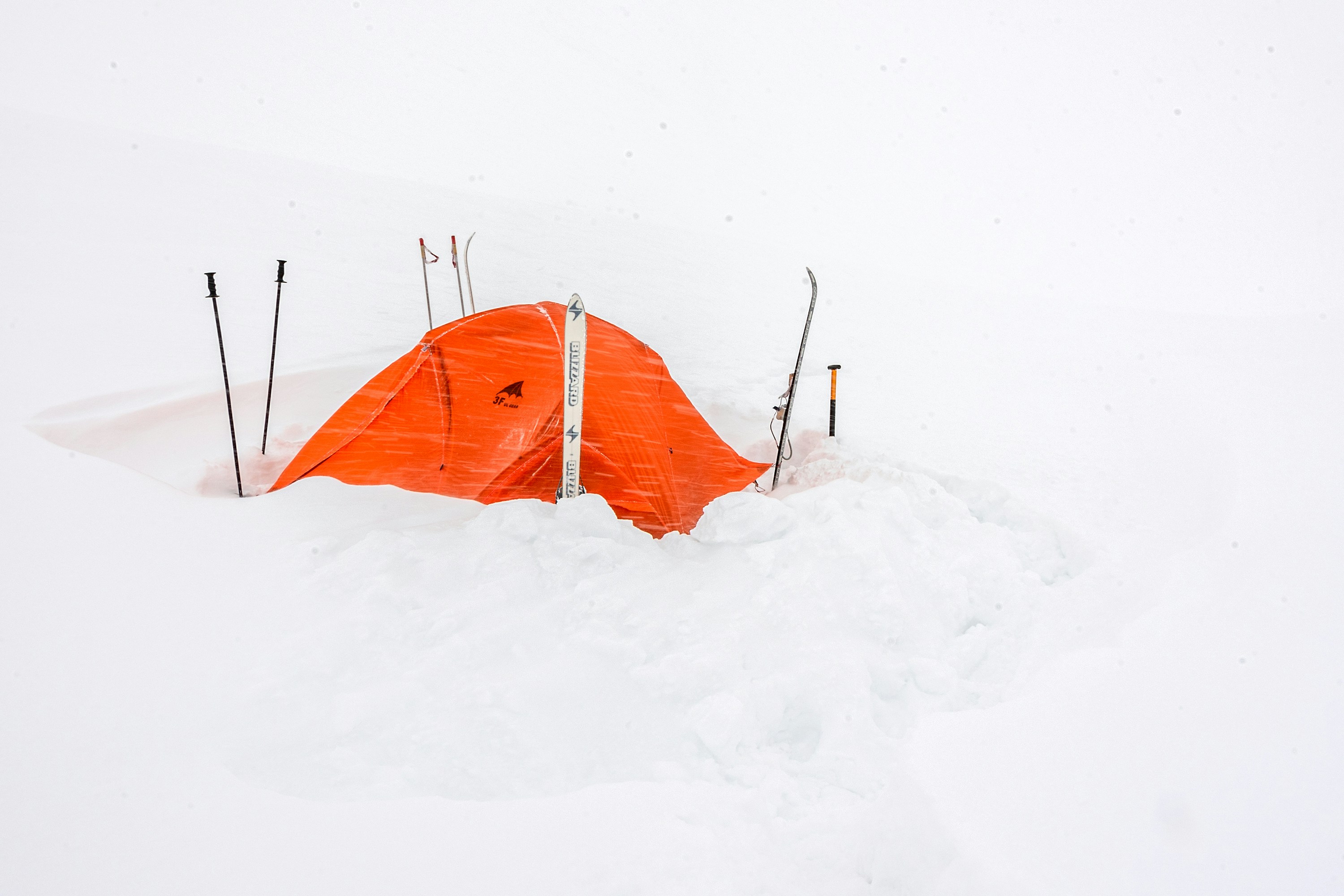 a tent in the snow with skis sticking out of it