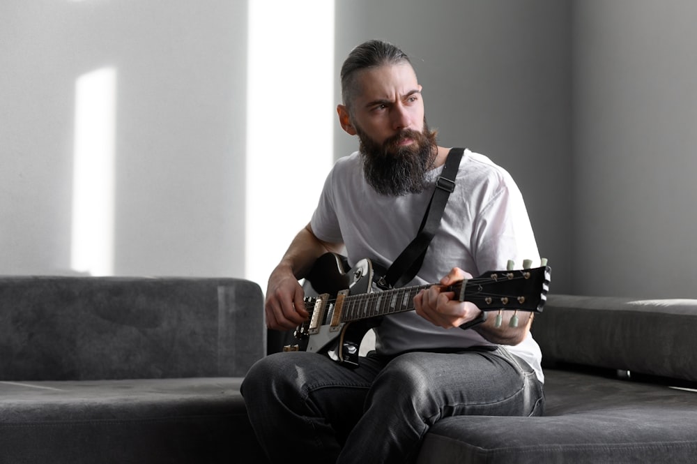 a man sitting on a couch playing a guitar