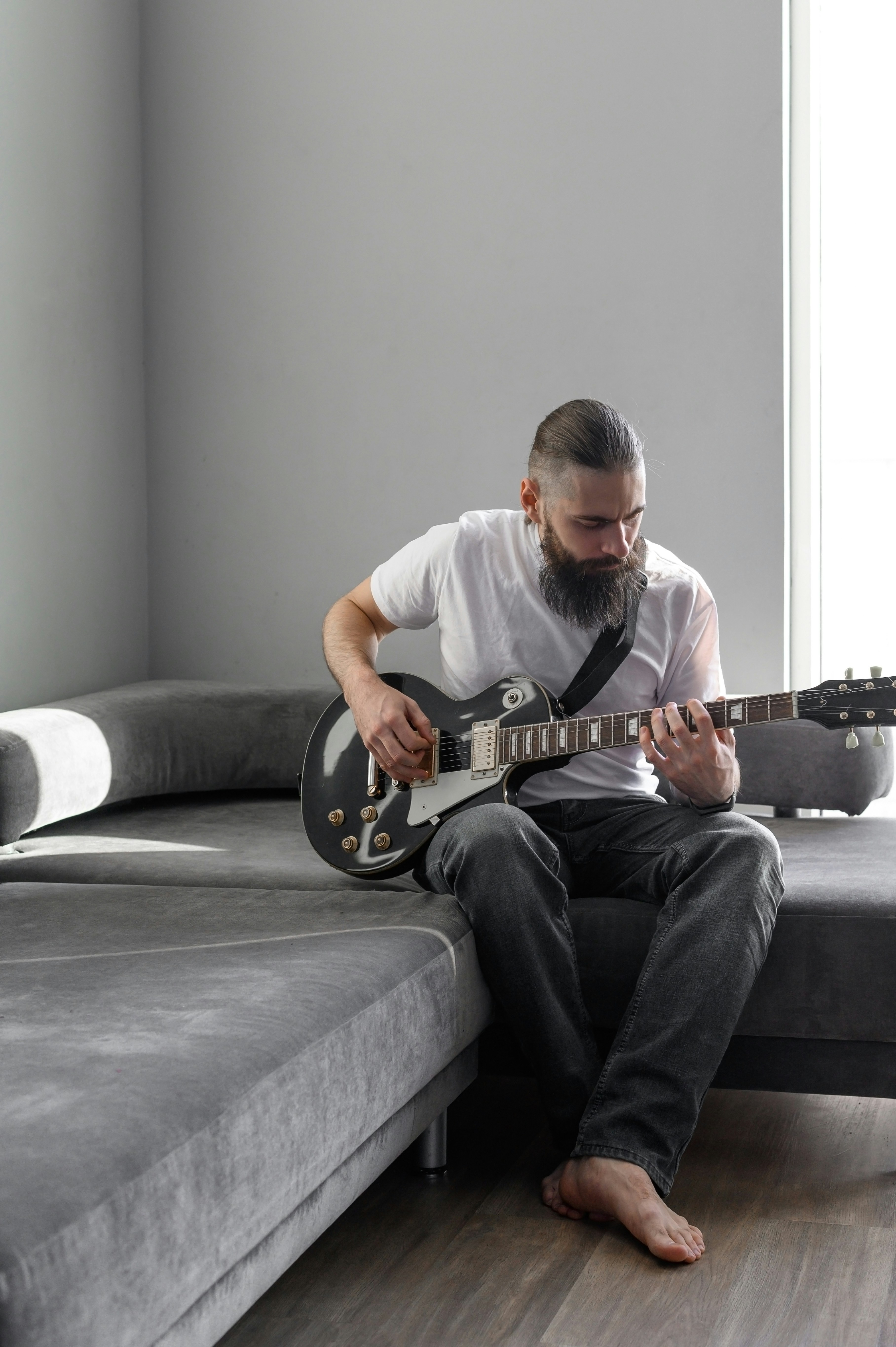 Un hombre sentado en un sofá tocando una guitarra
