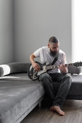 a man sitting on a couch playing a guitar