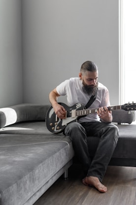 a man sitting on a couch playing a guitar