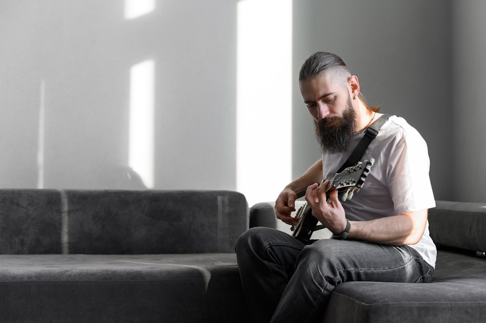 a man sitting on a couch playing a guitar