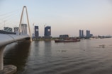A modern bridge under construction spanning a river in a developing area.