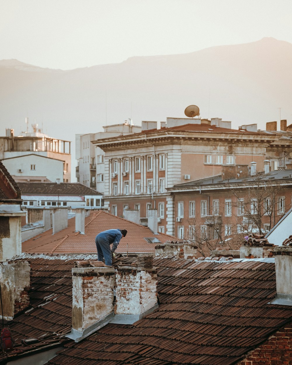 um homem de pé em cima de um telhado ao lado de um edifício alto