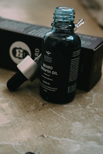 Close-up of amber-colored hair growth oil bottle with natural herbs around it.