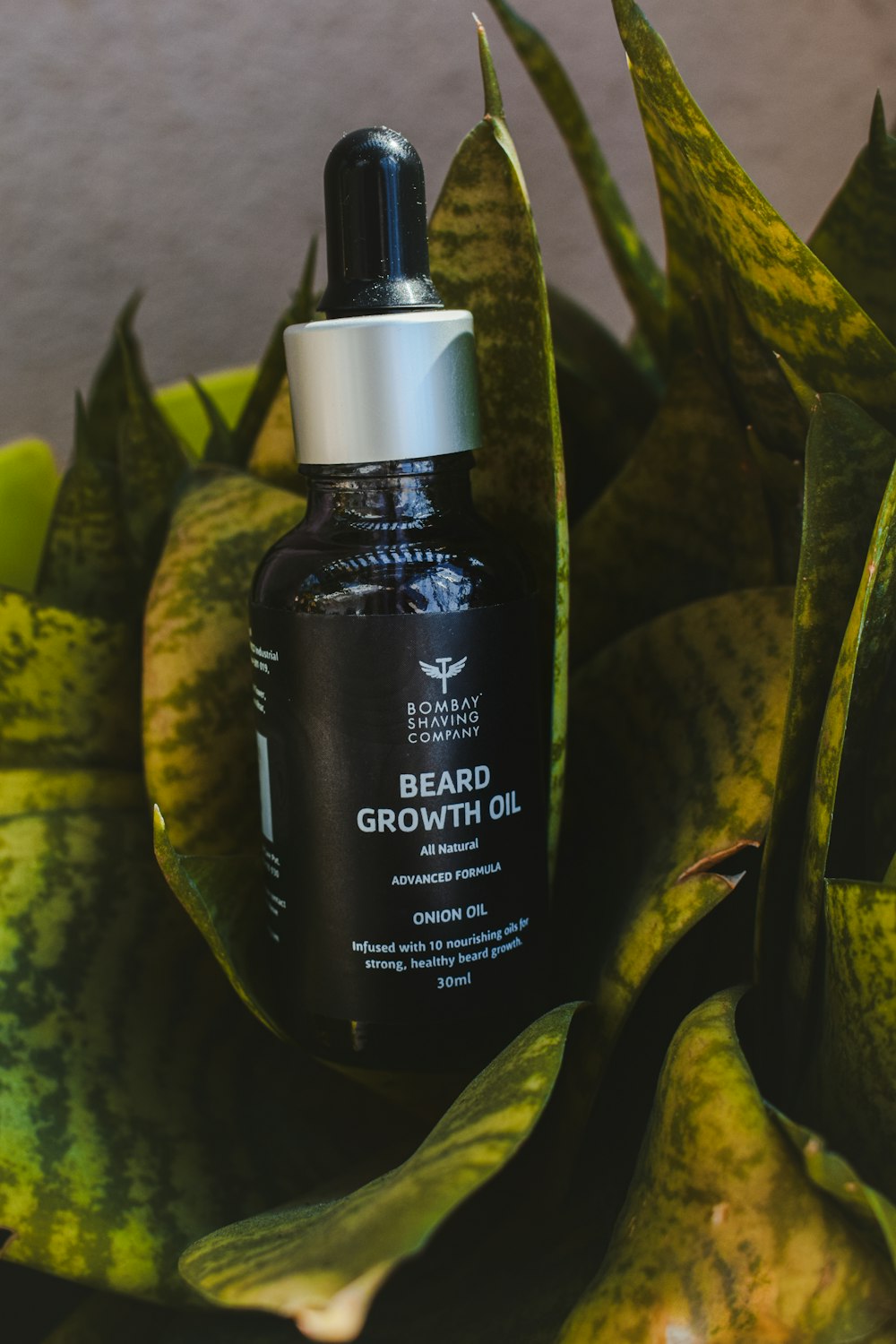 a bottle of beard growth oil sitting on top of a plant